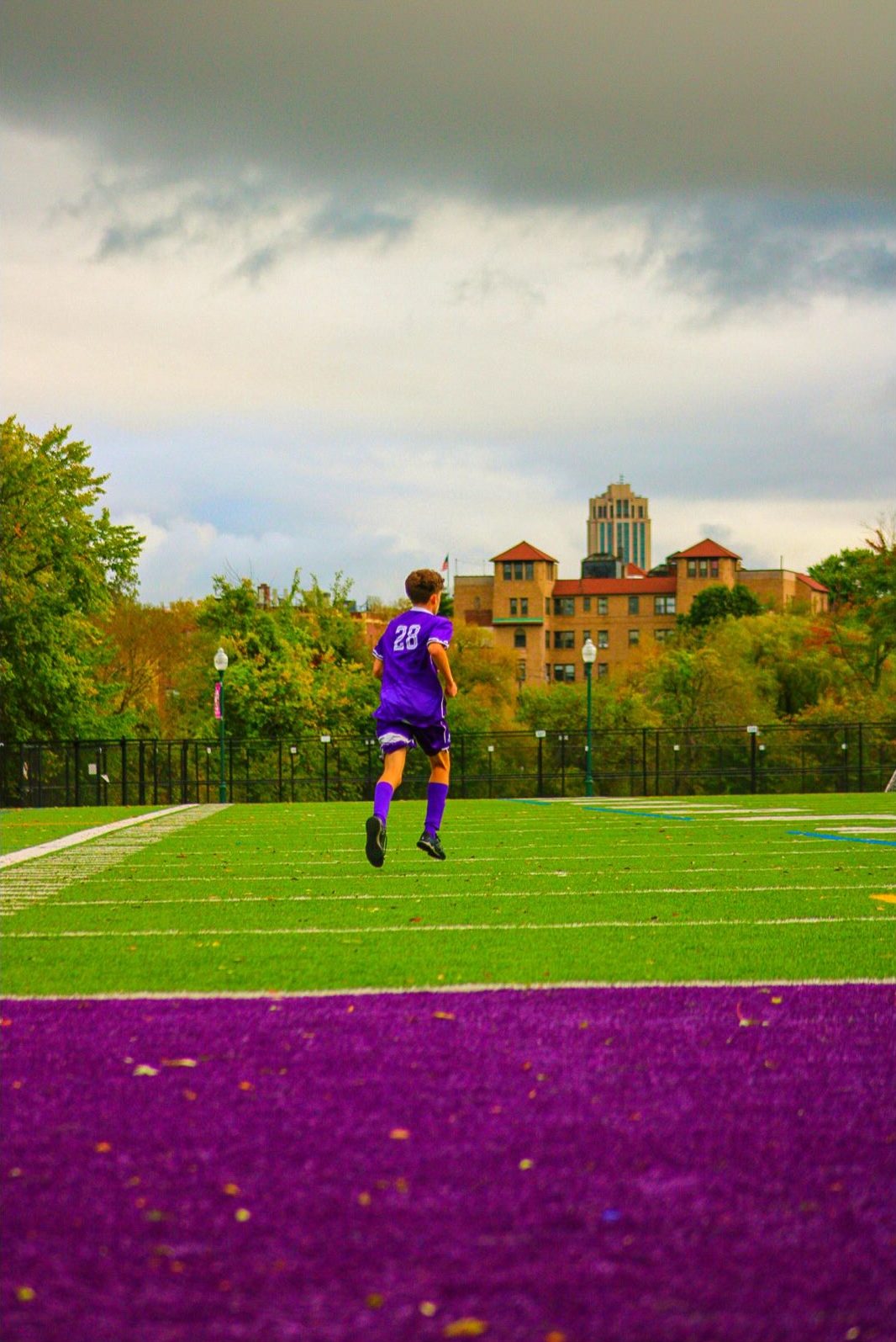 Player 28 sprinting down the touchline toward goal under an overcast sky